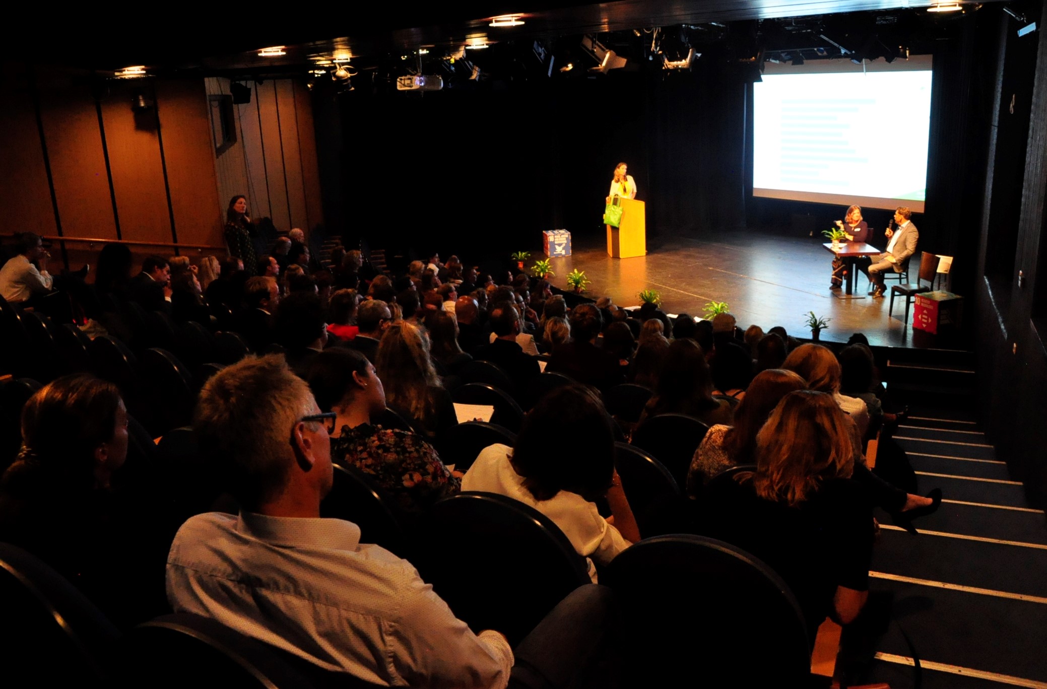 big audience hall with chairs and people listening to presentation